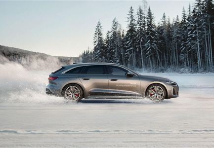 Ein Sportwagen fährt über eine verschneite Fläche. Im Hintergrund sind verschneite Bäume und eine klare Winterlandschaft zu sehen.