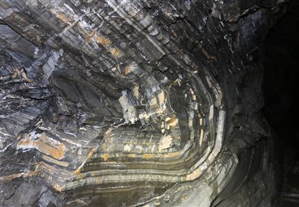 An impressive rock interior with clear layers and structural patterns. The colors range from gray to beige and display the natural formation.
