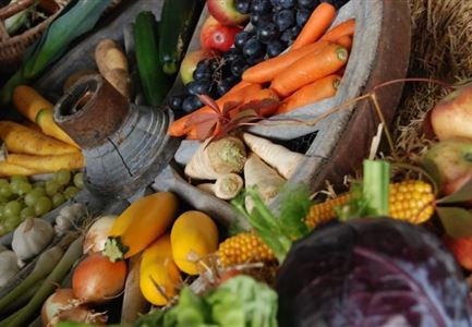 A colorful market stall with fresh fruits and vegetables. Among them are carrots, apples, grapes, and various types of vegetables.