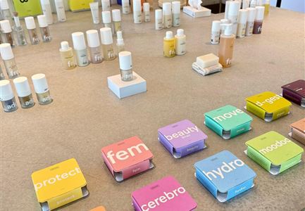 A selection of skincare products is arranged on a table. The products are visible in various colors and shapes, including bottles and boxes with decorative labels.