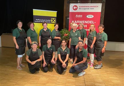Eine Gruppe von Frauen steht zusammen in Uniformen in einem Veranstaltungsraum. Im Hintergrund sind Banner und Pflanzen sichtbar.