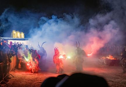 A spectacular night with mask wearers carrying torches and standing in colorful smoke. The atmosphere is festive and mysterious.