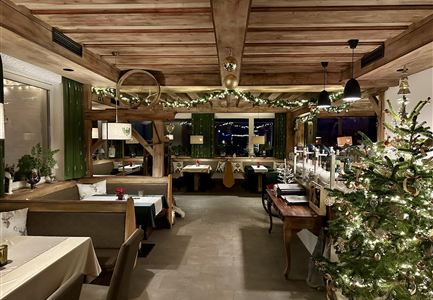 Ein gemütliches Restaurant mit rustikalem Holzdekor. Der Raum ist festlich dekoriert und hat einen geschmückten Weihnachtsbaum.