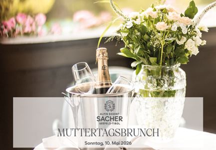 Ein eleganter Tisch mit einer Flasche Sekt im Kühlbehälter und zwei Gläsern. Nebenbei steht ein schöner Blumenstrauß in einer Vase.