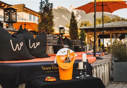 Een stijlvolle lounge met gezellige zitplaatsen en parasols. Op de tafel staat een champagne-ijsbucket van Veuve Clicquot.