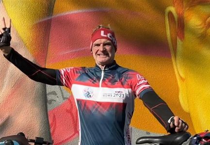 Ein Radfahrer hebt begeistert den Daumen. Im Hintergrund ist ein buntes Wandgemälde zu sehen.