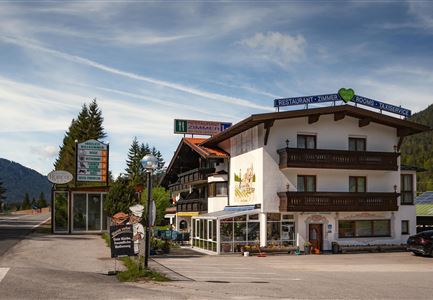 Ein kleines Gasthaus in einer ländlichen Umgebung. Es gibt viele Schilder und Bäume rund um das Gebäude.