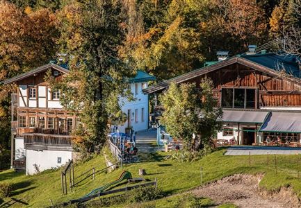 Ein malerisches Gebäude im ländlichen Raum, umgeben von buntem Herbstlaub. Die Architektur kombiniert traditionelle Holzelemente mit modernen Akzenten.