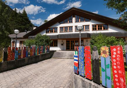 Ein charmantes Gebäude mit einem modernen, traditionellen Stil. Bunte Holzlatten säumen den Weg und verleihen dem Eingang eine freundliche Atmosphäre.