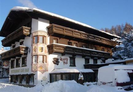 A stylish mountain restaurant with a traditional snow-covered exterior. The sky-blue sky creates a beautiful winter atmosphere.