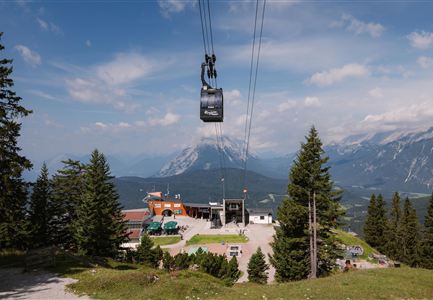 A mountain station with a cable car in the beautiful nature. In the background, majestic mountains can be seen under a clear sky.