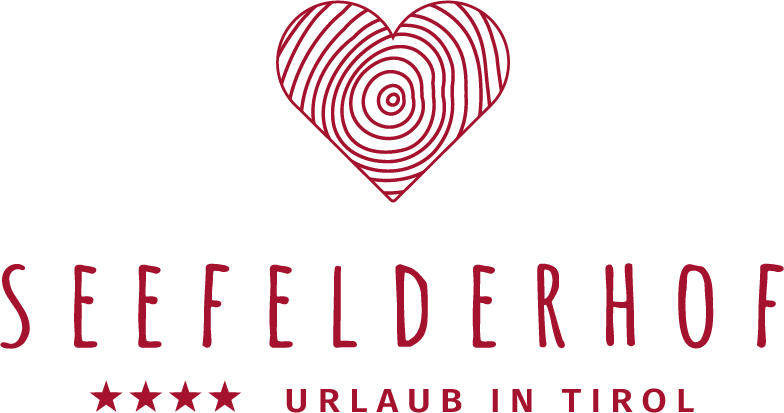 Das Logo des Seefelderhofs zeigt ein herzförmiges Design mit einer Holzstruktur. Es repräsentiert den Urlaub in Tirol und das vier Sterne Hotel.