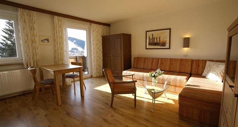 A bright living room with a cozy sofa and a wooden table. Large windows offer a beautiful view of the landscape.