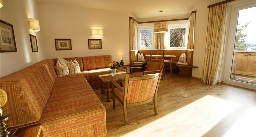 A cozy living room with a large sofa and a table. The light shines through the windows and creates a bright atmosphere.