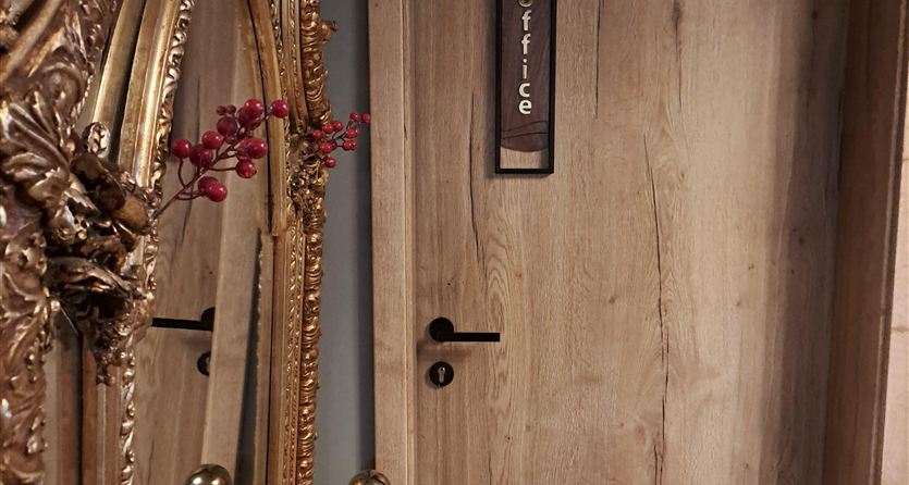 An elegant wooden door with a sign that says "Office." Next to the door is a lovely, golden mirror.