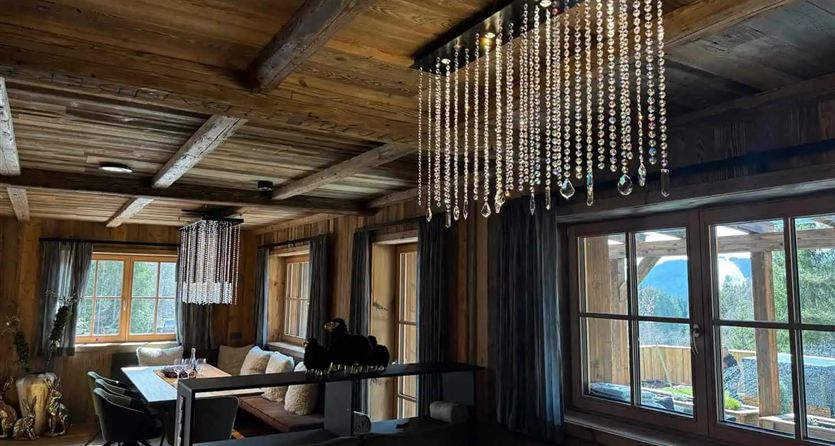 Een gezellige kamer met houten wanden en grote ramen die veel licht binnenlaten. Plafondverlichting met kristallen zorgt voor een elegante sfeer.