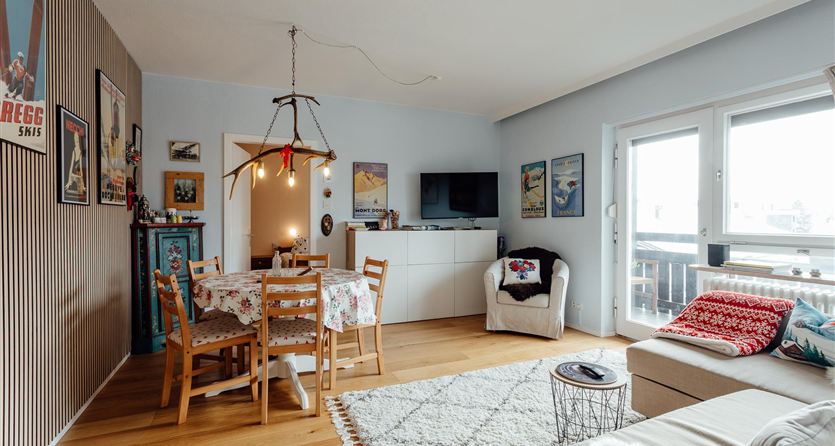 Un soggiorno accogliente con un tavolo da pranzo e sedie. Grandi finestre portano molta luce nell'ambiente e c'è una decorazione rilassata.