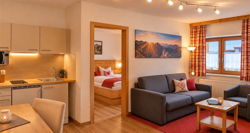 A cozy apartment with modern furnishings. There is a kitchen, a living area, and a bedroom with a window that lets in a lot of light.