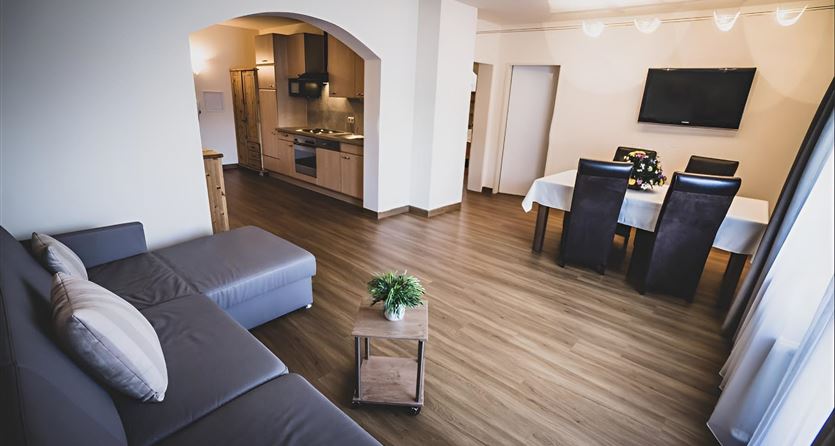 Een moderne woonkeuken met parketvloer en een comfortabele bank. Het eethoek is goed ingericht en biedt plaats voor meerdere personen.