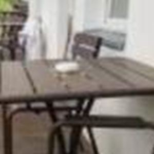 A balcony with brown furniture and a view of the green landscape. The table is set and offers space for relaxation.