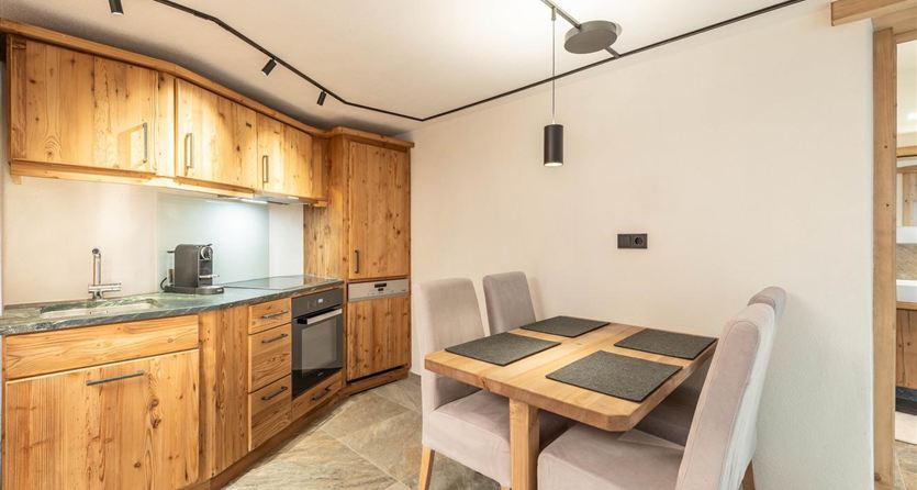 Una cucina moderna con mobili in legno e un piccolo gruppo da pranzo. La stanza è ben illuminata e ha un'atmosfera accogliente.