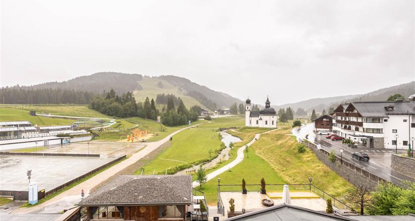 A tranquil landscape with gentle hills and a small church. The sky is gray and it is drizzling lightly.