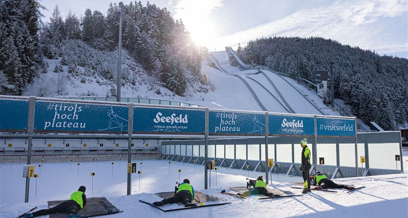 A winter sports facility with snow-covered slopes and a ski jump. Some athletes are getting ready for training.