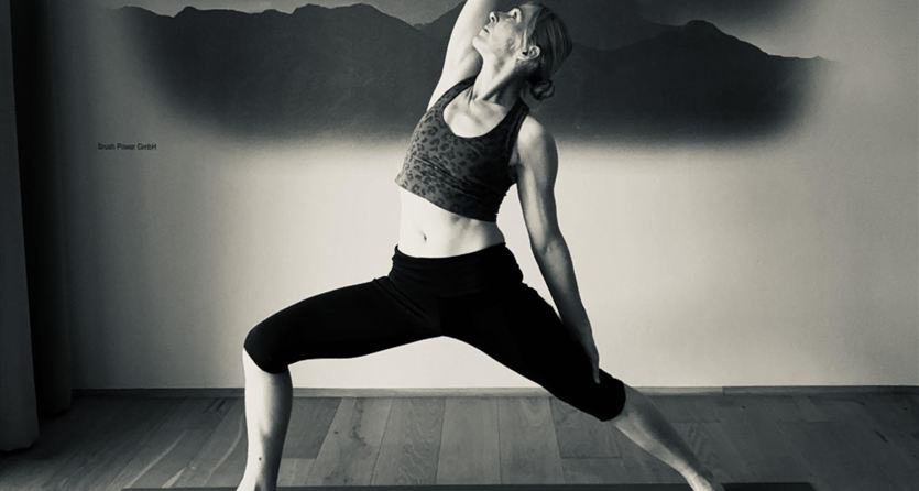A woman is doing a yoga pose in a modern room. In the background, stylized mountains can be seen.