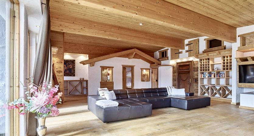 Un soggiorno elegante con soffitti in legno e un divano moderno. Le grandi finestre portano molta luce diurna nella stanza.