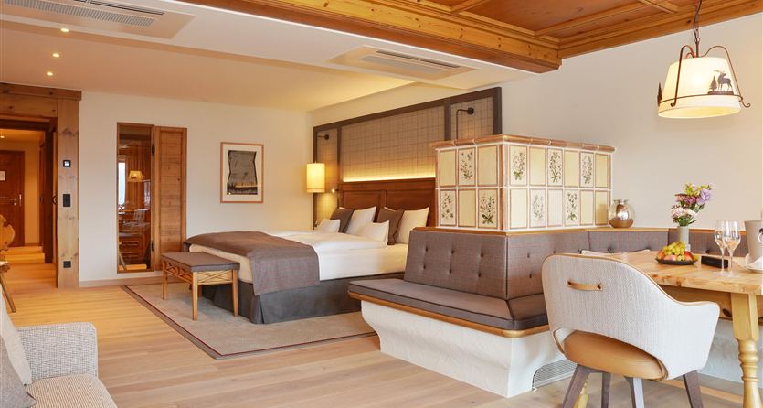 Ein modernes Hotelzimmer mit einem großen Bett und gemütlichen Sitzgelegenheiten. Die Holzdecke und warmen Farben schaffen eine einladende Atmosphäre.