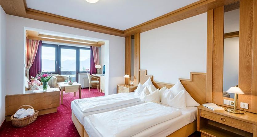 Ein gemütliches Hotelzimmer mit zwei Einzelbetten und einem schönen Ausblick. Die Einrichtung besteht aus Holz und das Zimmer ist hell und einladend.