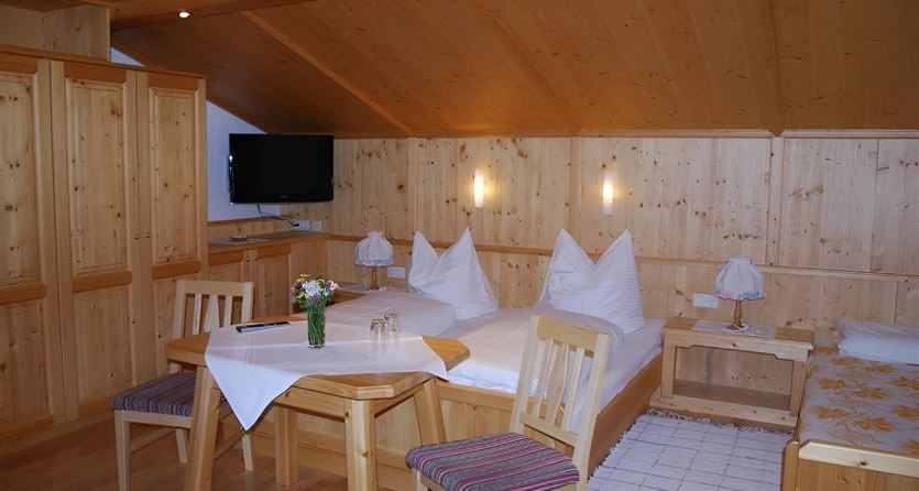Een gezellige hotelkamer met houtafwerking. Het bevat twee bedden, een tafel en een televisie.