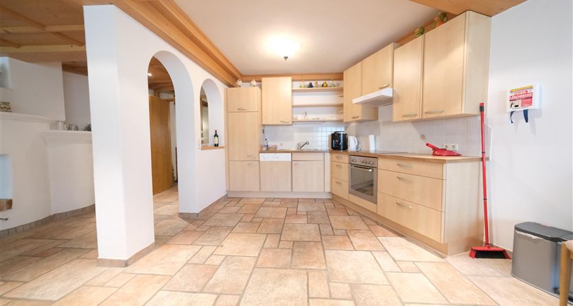 Een moderne keuken met een houten en tegels vloer. Ze is goed uitgerust en helder verlicht.