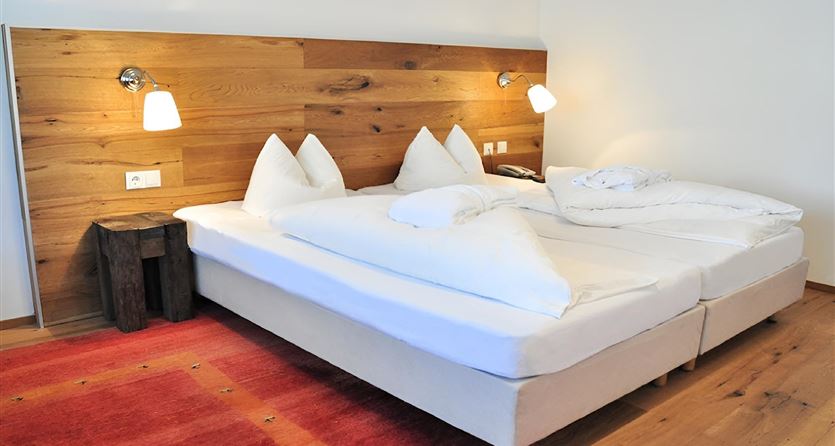 A cozy bedroom with a large double bed and wood paneling. Two bedside lamps provide pleasant lighting.