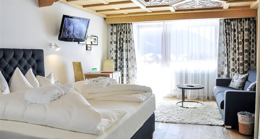 A cozy hotel room with a large bed and a sofa.  
Large windows let in plenty of light and offer a beautiful view.