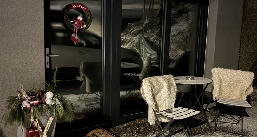 Een stijlvolle kamer met een groene kast, een televisie en decoraties zoals een lichtsnoer. Boven is een kerstguirlande met kleine sterren zichtbaar.