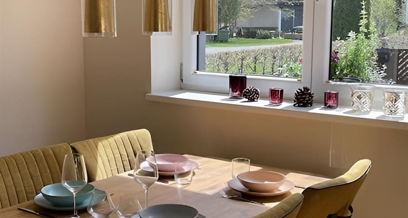 A stylish dining area with a wooden table and comfortable chairs overlooking the greenery.