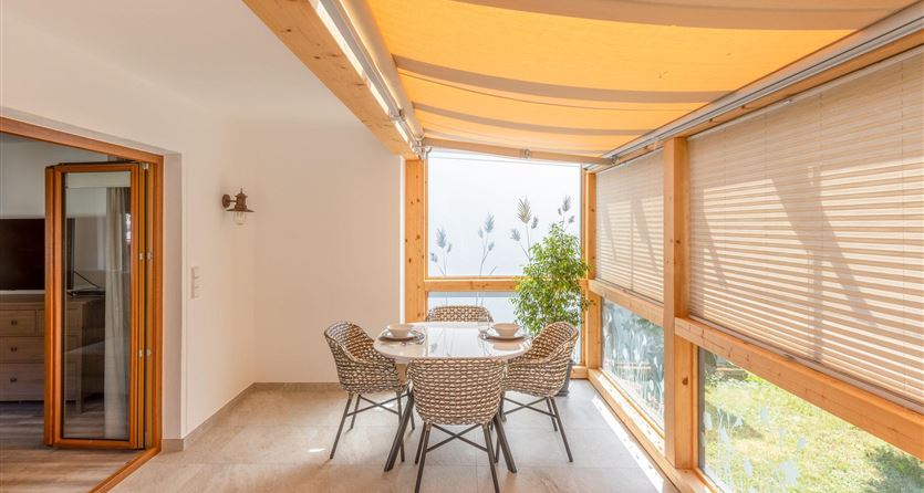 Een lichte eetkamer met een ronde tafel en stoelen. Grote ramen bieden een mooi uitzicht naar buiten.