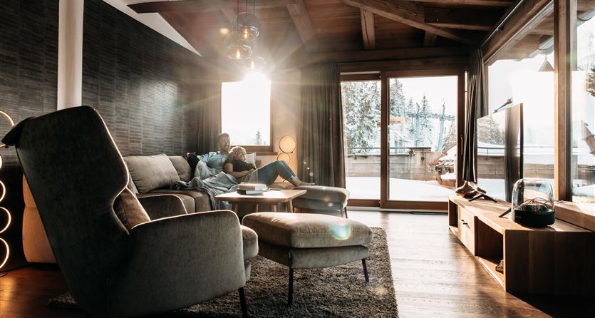 Ein modernes Wohnzimmer mit bequemen Möbeln und viel natürlichem Licht. Der Ausblick zeigt eine winterliche Landschaft durch große Fenster.