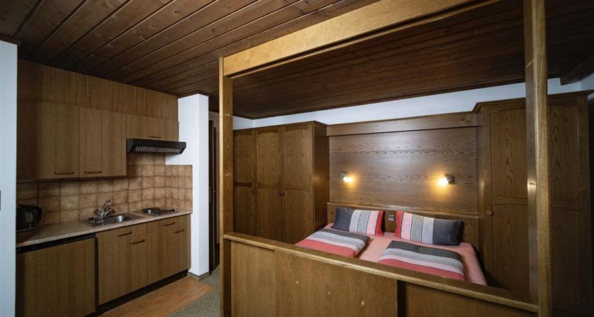 Ein gemütliches Schlafzimmer mit einem angrenzenden kleinen Küchenbereich. Die Holzelemente und warmen Farben schaffen eine einladende Atmosphäre.