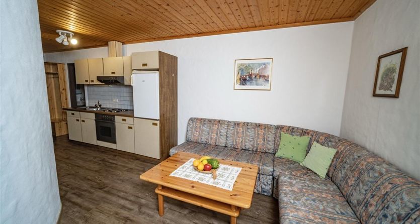 Eine gemütliche Wohnung mit einer Couch und einem Tisch. Die Küche ist funktional und gut ausgestattet.