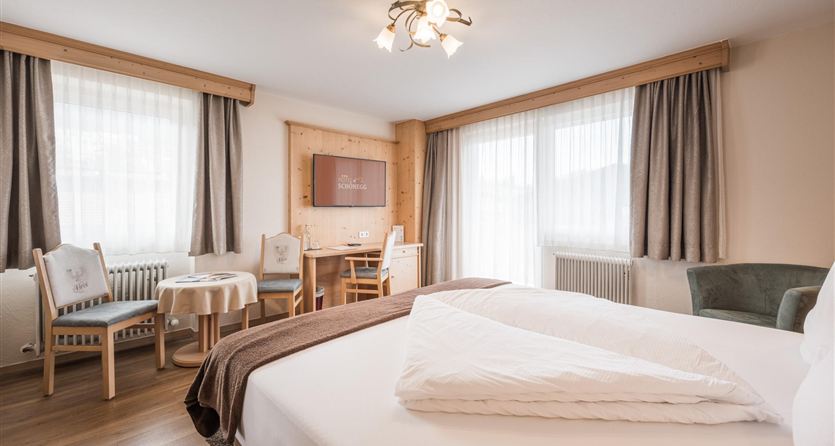 Una stanza luminosa e moderna con un grande letto e una confortevole area salotto. Grandi finestre garantiscono molta luce naturale e un'atmosfera accogliente.
