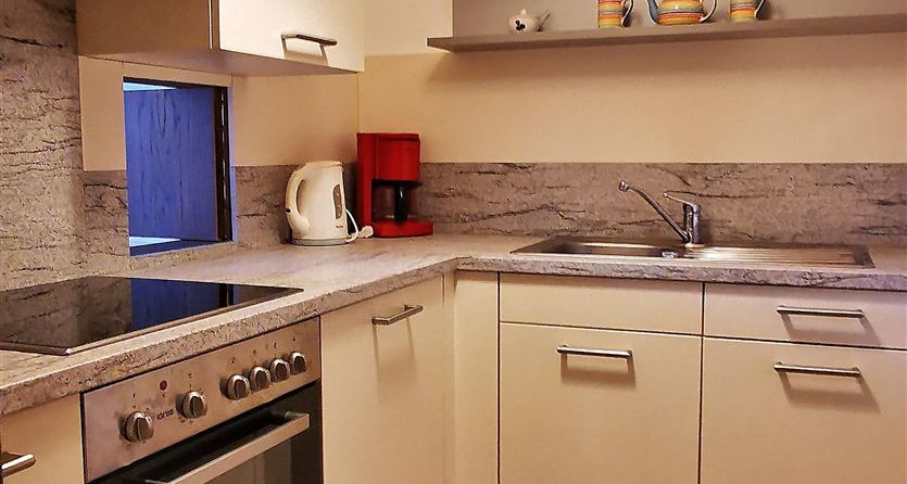 A modern kitchen with bright cabinets and a simple design. It is well-equipped with a stove, refrigerator, and a countertop.