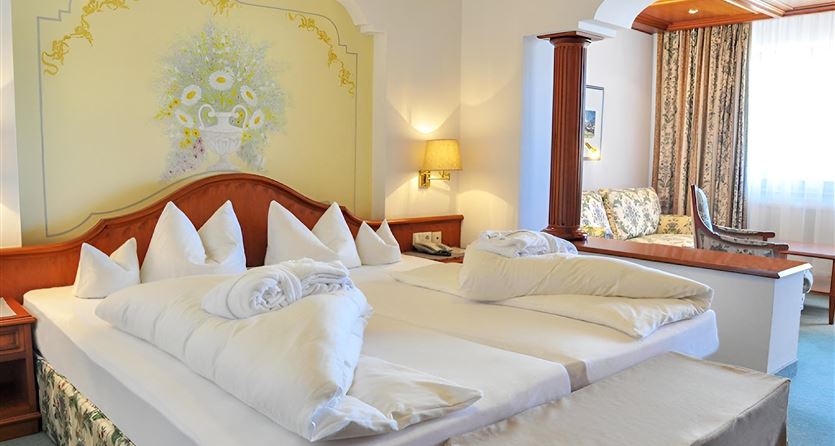 A modern bedroom with a large double bed and elegant furnishings. The walls are painted light and decorated with a beautiful mural.