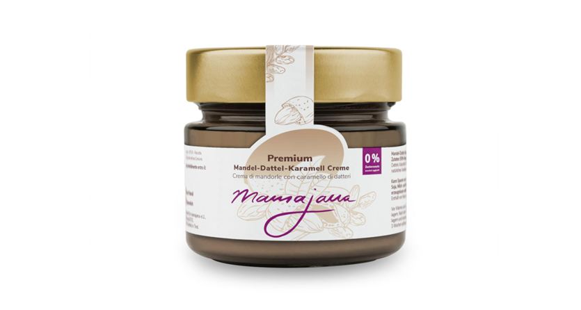 Un vaso di crema di caramello premium alle mandorle e datteri con coperchio dorato. Il packaging è elegante e mostra il marchio "maunajana".