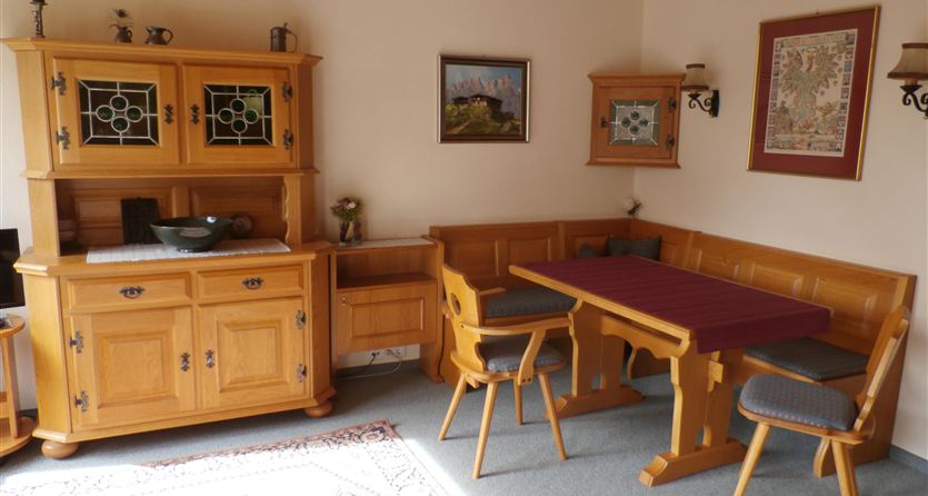Een gezellige eethoek met een houten tafel en stoelen. De muren zijn versierd met afbeeldingen en decoratieve elementen.