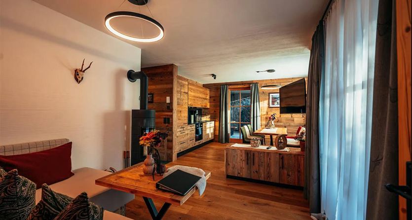 Een gezellige kamer met houten muren en moderne meubels. Grote ramen laten veel daglicht binnen en bieden een uitzicht naar buiten.