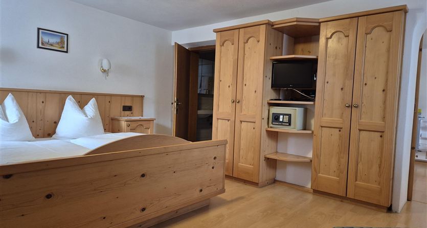 Una camera d'hotel accogliente con mobili in legno e un grande letto. Nel locale ci sono una TV e un frigorifero.