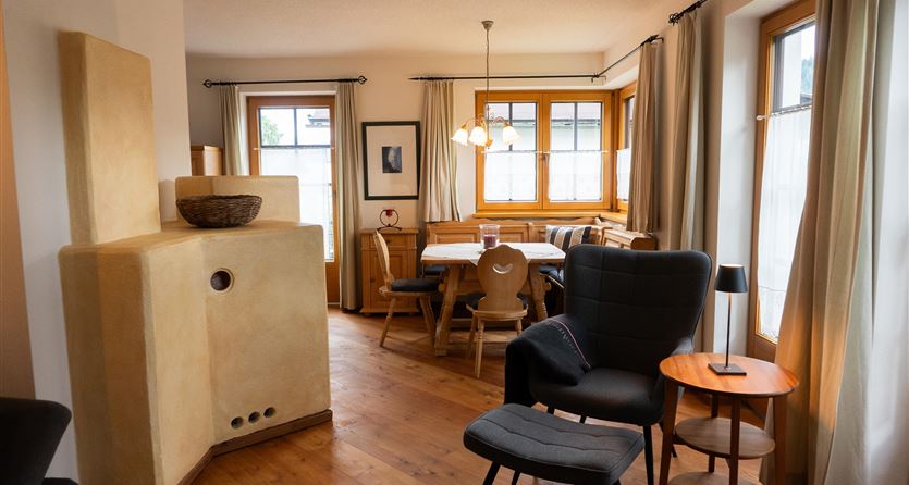 Ein gemütlicher Wohnraum mit einem Essbereich und großen Fenstern. Moderne Möbel und warme Holztöne schaffen eine einladende Atmosphäre.