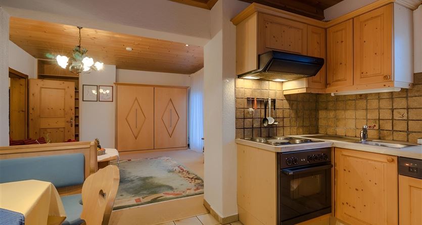 Eine gemütliche Küche mit Holzschränken und einem modernen Herd. Der Raum hat einen einladenden Wohnbereich mit einem Esstisch.